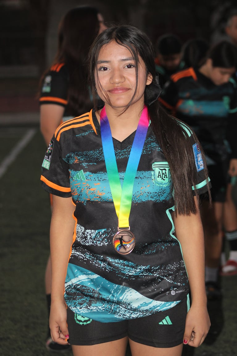 Young athlete wearing sports uniform and rainbow medal around neck at competitive event