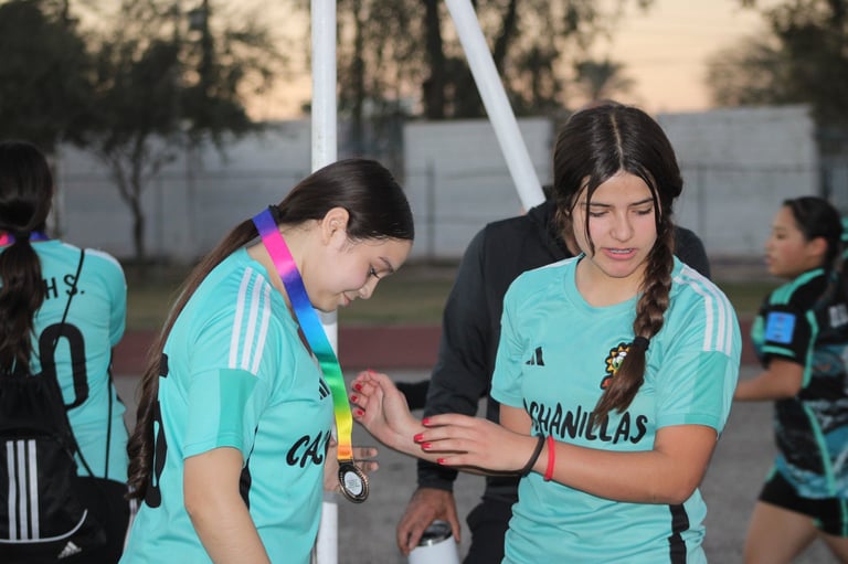 Coach instructing young female soccer players in turquoise uniforms during outdoor training session