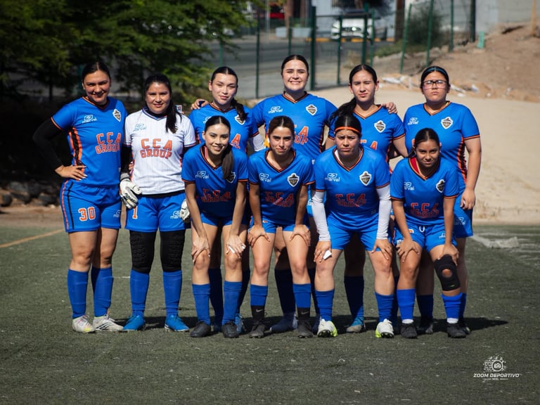 Womens soccer team in blue uniforms posing together on a field for a group photo