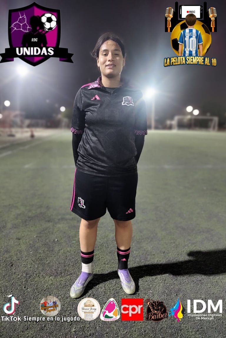 Soccer player in black and purple Adidas uniform standing on field at night with team logos and sponsors visible