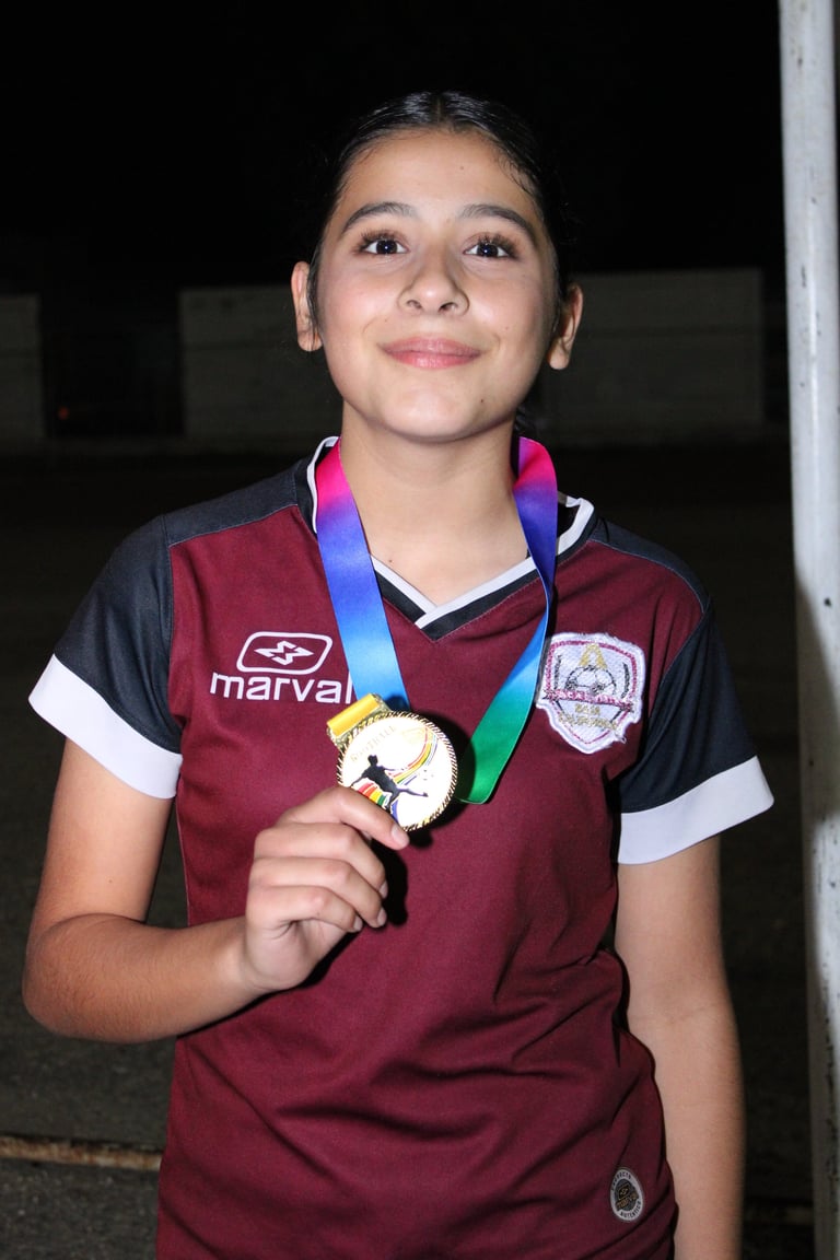 Young athlete in maroon and black sports jersey holding gold medal on rainbow ribbon