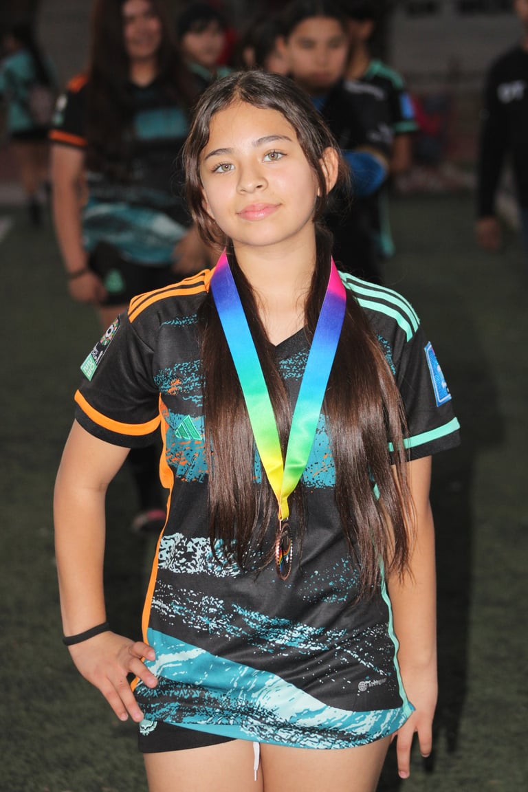 Young girl wearing a black and turquoise sports jersey with orange stripes, displaying a rainbow medal around her neck