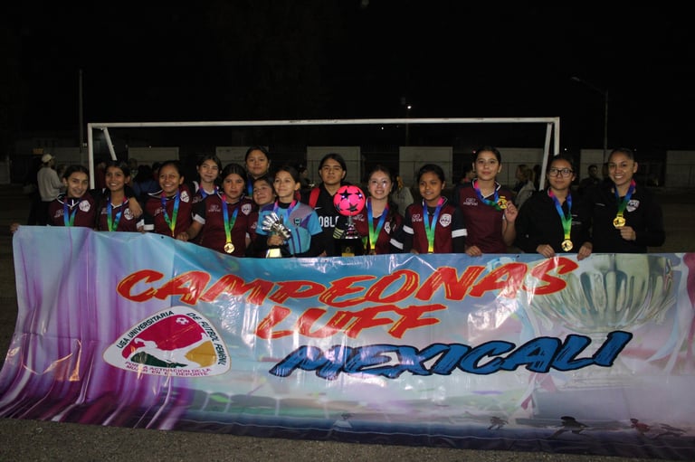 Group of young female athletes wearing medals standing behind a banner at a sports event celebration