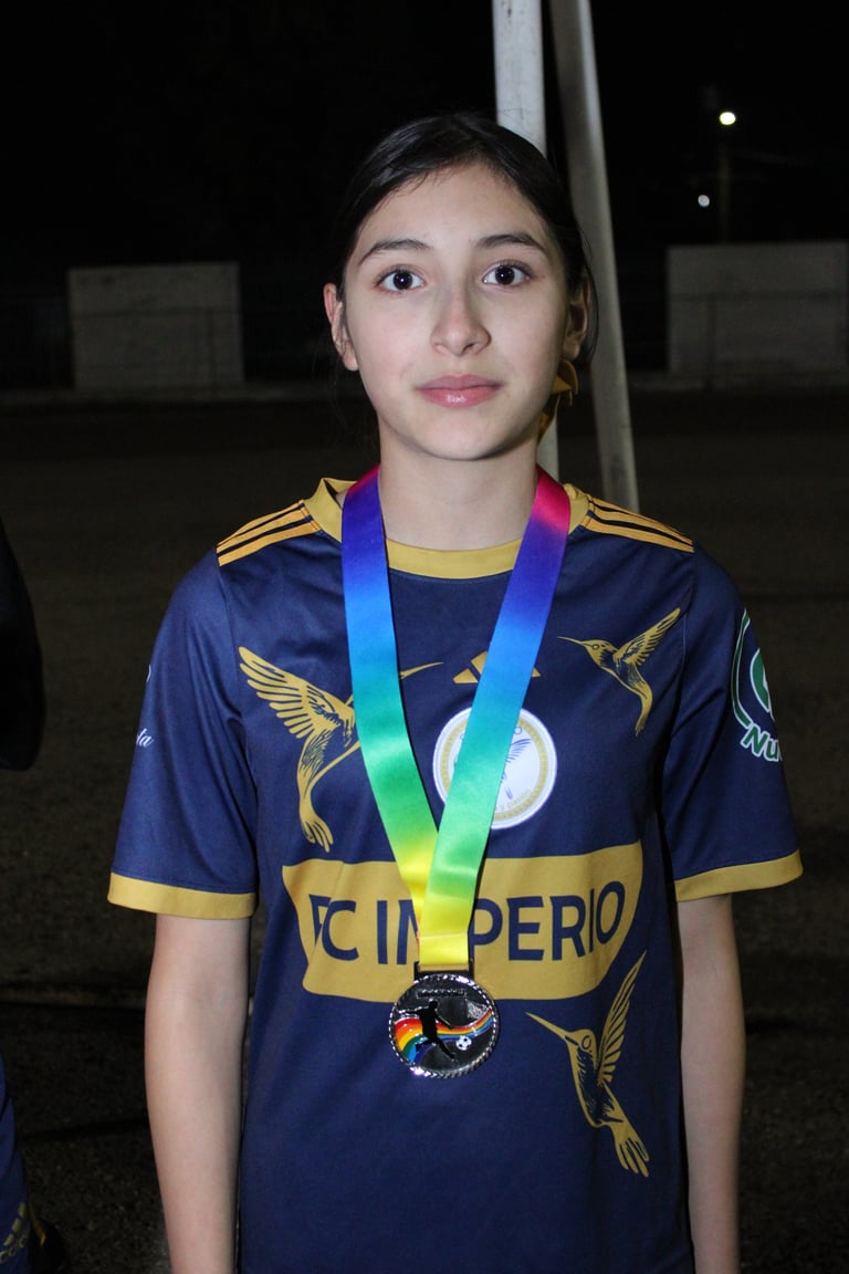 Young athlete wearing navy and gold sports jersey with rainbow medal around neck at night