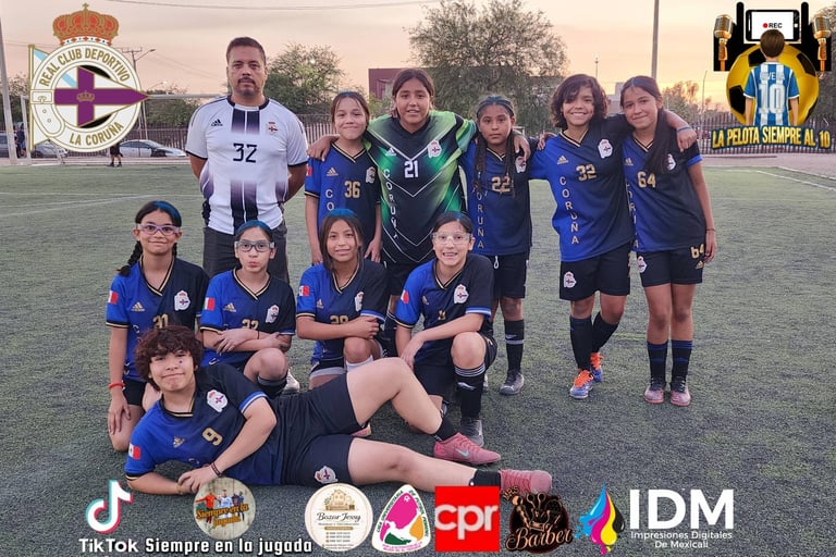 Youth girls soccer team in blue uniforms posing on field with coach wearing number 32, sponsor logos at bottom
