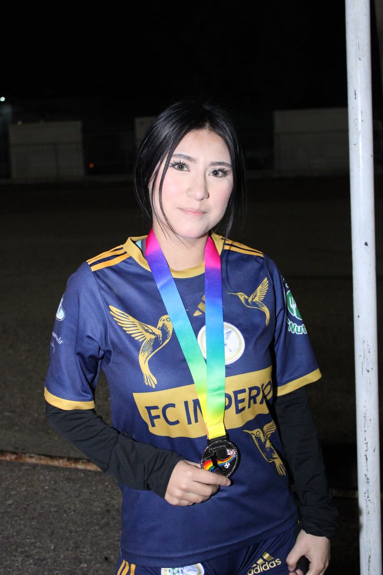 Young woman wearing navy blue sports jersey with gold accents and rainbow medal around neck at night