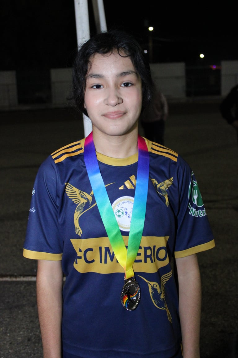 Young athlete wearing navy and gold sports jersey with medal around neck, standing at night outdoors