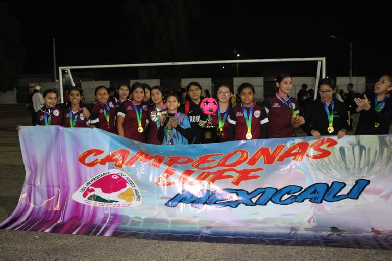 Group of young athletes wearing medals standing behind a colorful banner at a sporting event