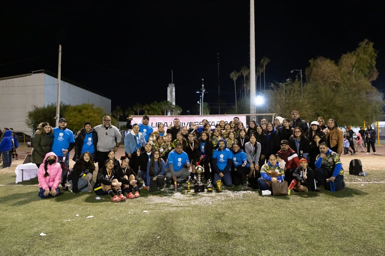 Large group of people wearing blue shirts gathered on grass at night for a community event or team gathering