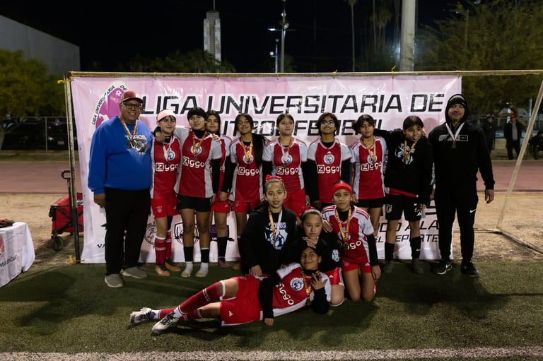 Youth soccer team in red jerseys posing with trophy at championship celebration event
