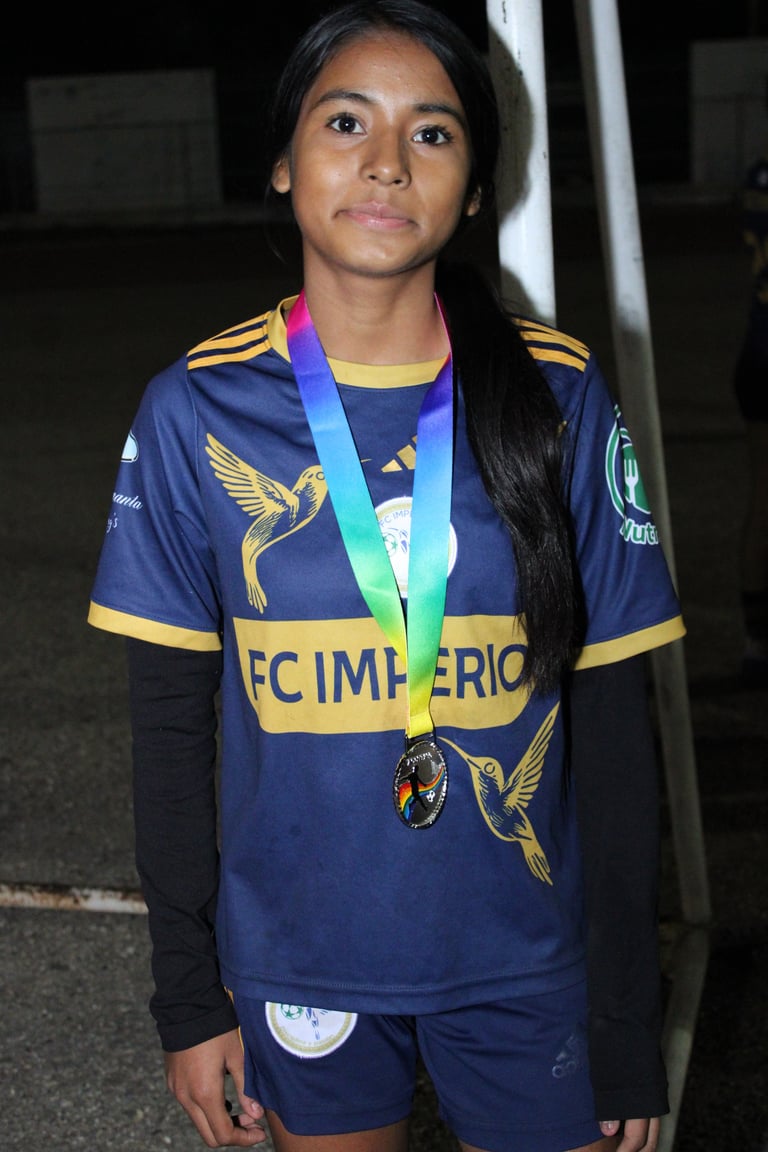 Young athlete wearing a navy blue and yellow sports jersey with a rainbow medal around her neck