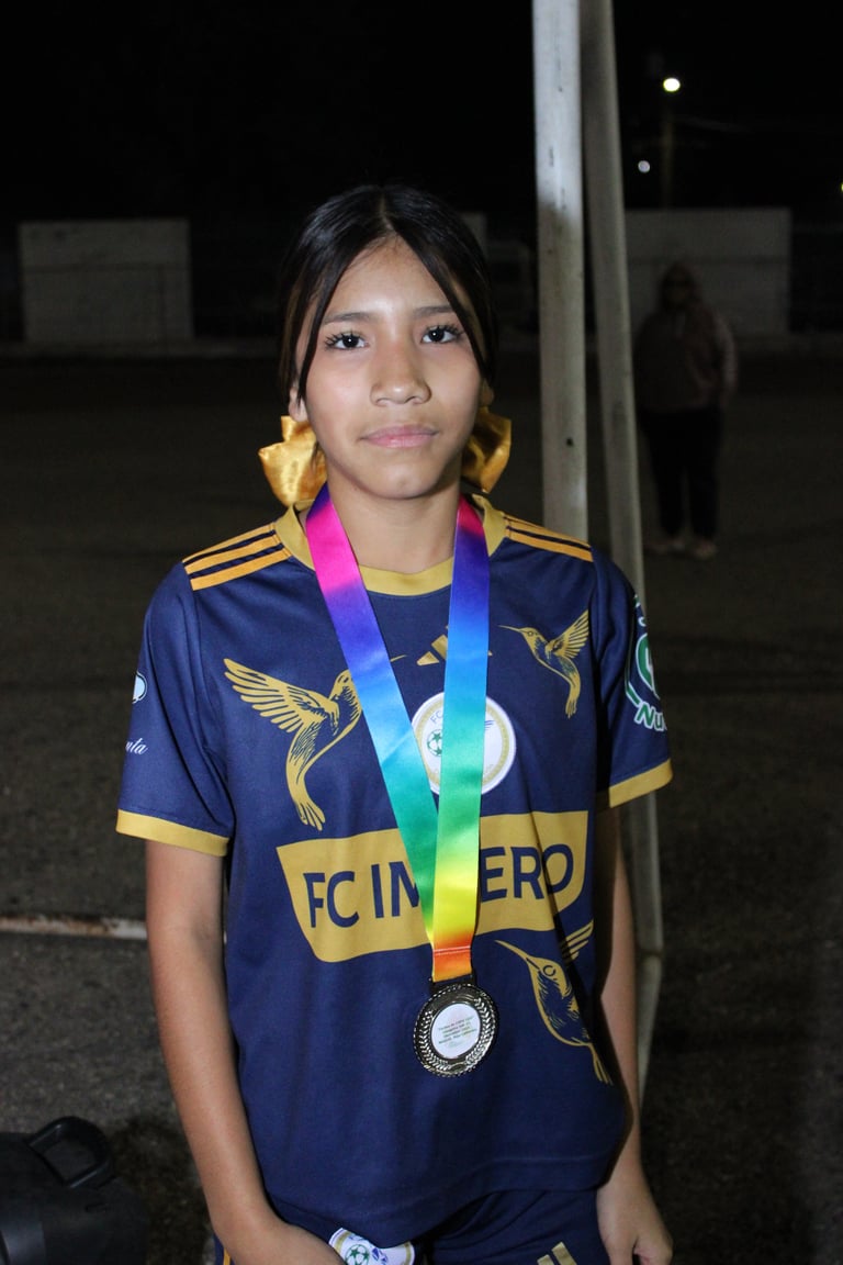 Young athlete wearing navy sports jersey with gold bird design and rainbow medal around neck at night