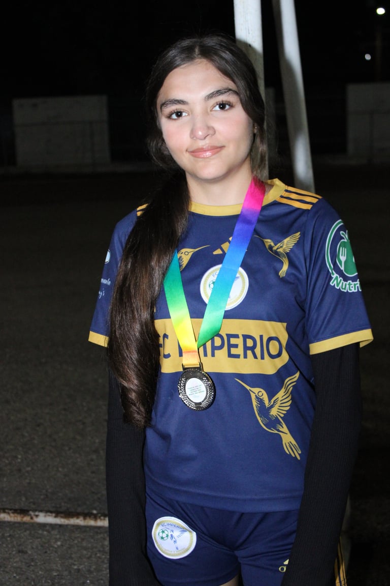 Young athlete wearing dark blue and gold sports uniform with rainbow medal around neck at night