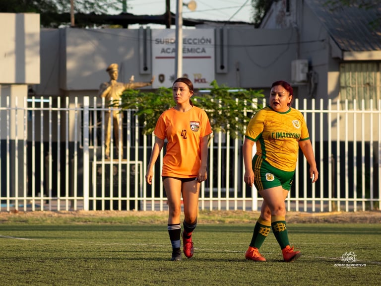 Two young female soccer players in yellow and green jerseys jogging on a grass field during practice