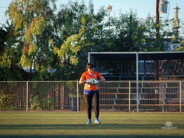 Runner in orange shirt jogging on grass field with fence and trees in background