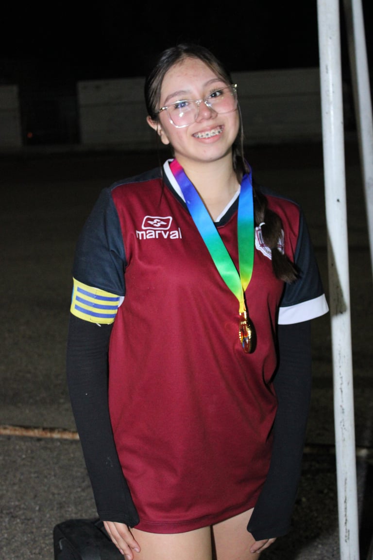 Smiling young athlete wearing burgundy and navy sports uniform with striped armband, displaying a rainbow medal around her neck