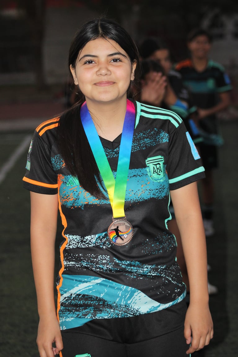 Young athlete wearing black sports jersey with turquoise and orange accents, proudly displaying a rainbow medal around her neck