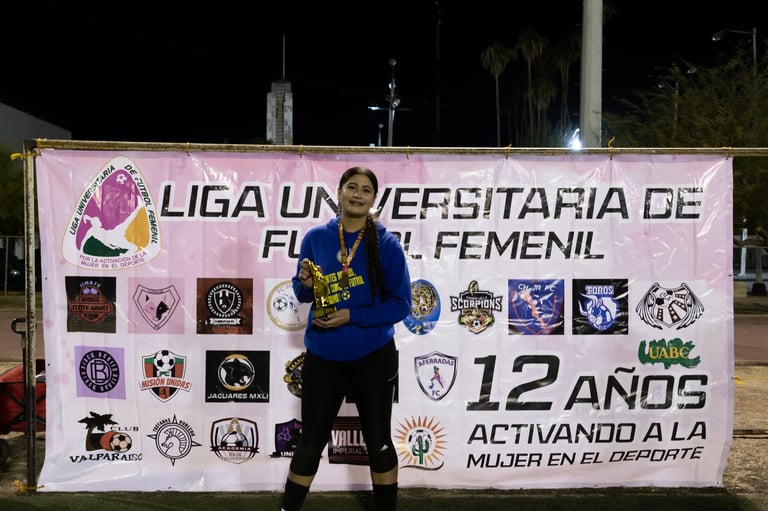 Female athlete holding trophy at womens university soccer league event banner celebrating 12 years of women in sports