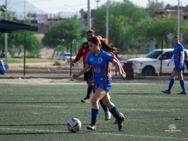 Female soccer players competing for the ball during a match on an outdoor field