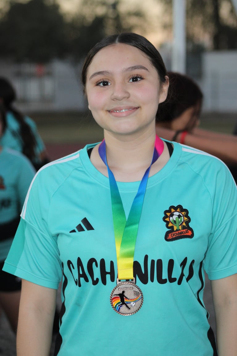 Young athlete wearing turquoise sports jersey with medal around neck, smiling at camera outdoors